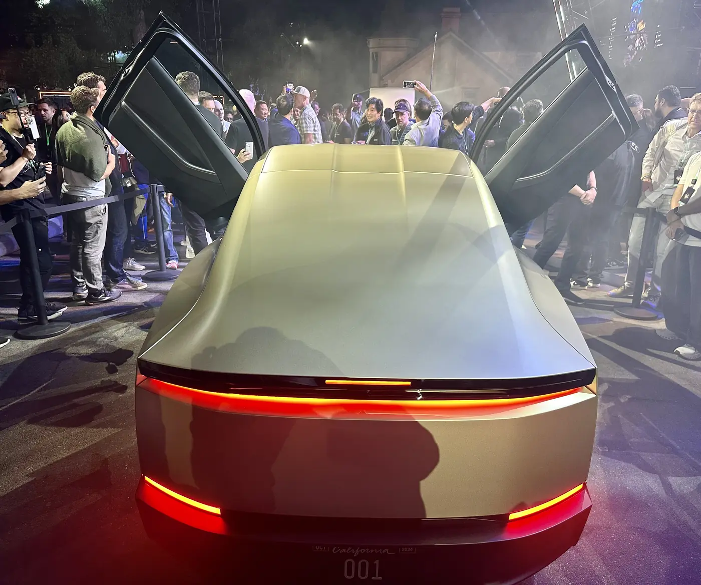 Rear view of a silver Cybercab, with a full-width light bar across the back.